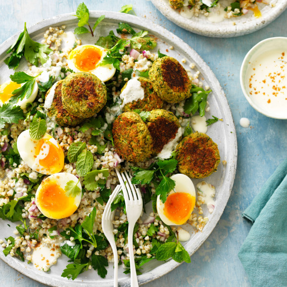 Baked falafel on plate with salad, fresh herbs and eggs