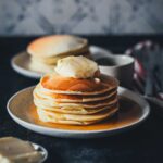 Pancakes – mein absolutes Lieblingsrezept seit über 15 Jahren. Einfach ein Stapel Pancakes mit Butter und Ahornsirup serviert auf einem kleinen Teller | moeyskitchen.com