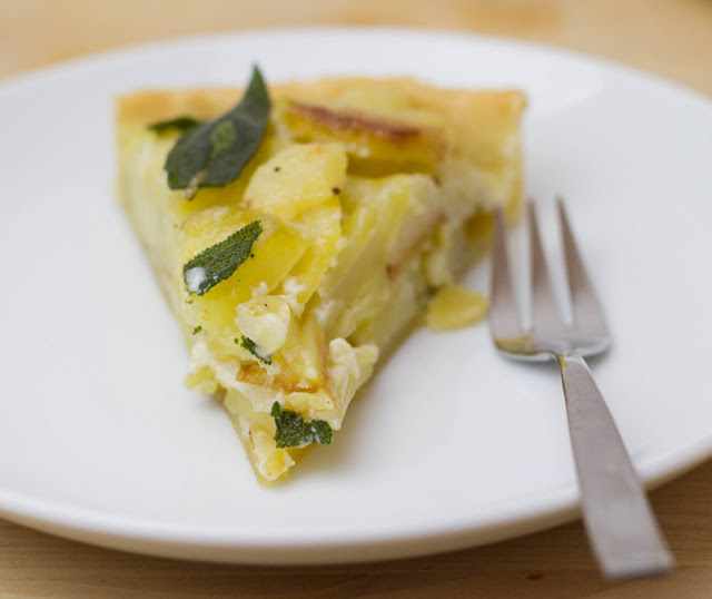ein Stück frisch gebackene Tarte mit knusprigen Bratkartoffeln, Creme fraiche und Salbei