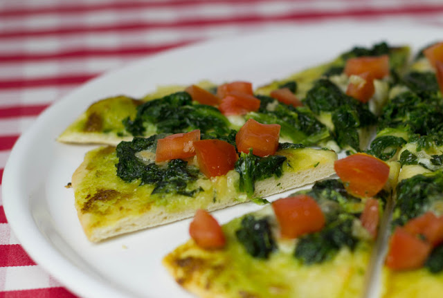 Rezept für Pesto-Spinat-Pizza mit Tomaten und Knoblauchöl wie von Vapiano frisch angeschnittene Pizza mit Pesto, Spinat, Knoblauchöl und Tomatenwürfeln