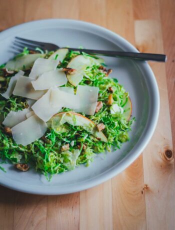 Rosenkohlsalat mit Apfel, Walnüssen und Pecorino – frischer Wintersalat auf einem Teller