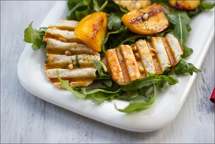 Sommersalat mit Halloumi-Chips und gegrillten Pfirsichen Angemachter Rucola-Salat mit knusprigen Chips aus Halloumi, gegrillten Pfirisichen, Kräutern und Zedernüssen
