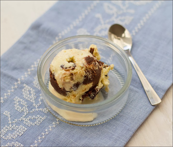 Sahniges Vanilleeis mit Schoko-Erdnüssen und Schoko-Fudge Eine Kugel Vanilleeis mit Schoko-Erdnüssen und Schoko-Fudge, serviert in einem Gläschen.