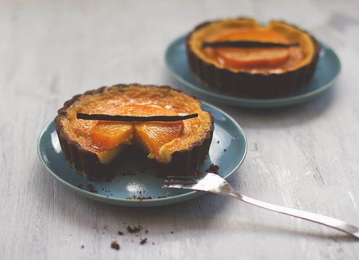 Angeschnittene kleine Tartelettes mit einer Füllung aus weißer Schokolade, belegt mit Kaki und Vanillesirup beträufelt