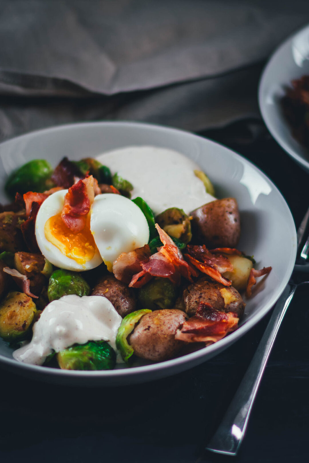 Hier teile ich mein Rezept für eine deftige Rosenkohl-Kartoffel-Pfanne. Serviert mit wachsweichem Ei, knusprigem Bacon und würzigem Knoblauch-Schmand. Perfekt für die schnelle Feierabendküche in Herbst und Winter! | moeyskitchen.com