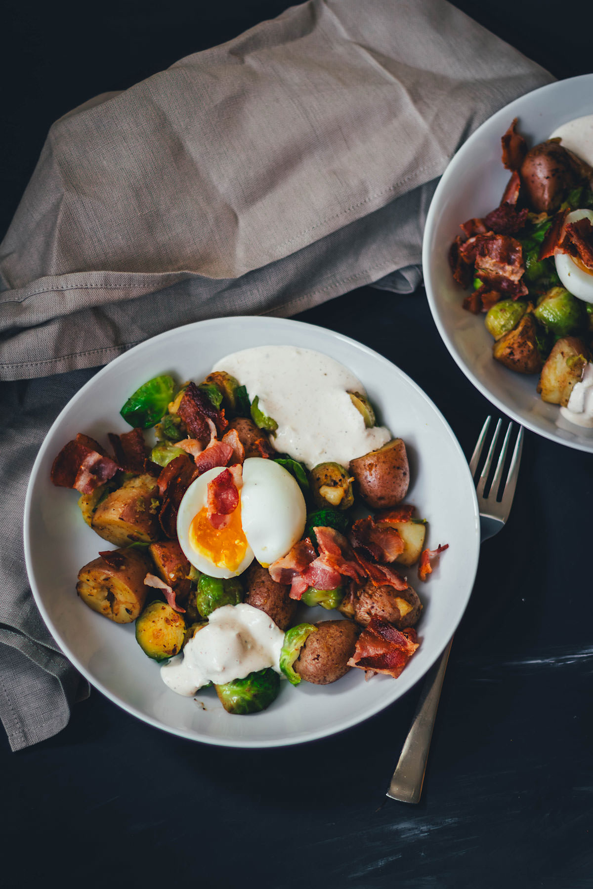 Hier teile ich mein Rezept für eine deftige Rosenkohl-Kartoffel-Pfanne. Serviert mit wachsweichem Ei, knusprigem Bacon und würzigem Knoblauch-Schmand. Perfekt für die schnelle Feierabendküche in Herbst und Winter! | moeyskitchen.com