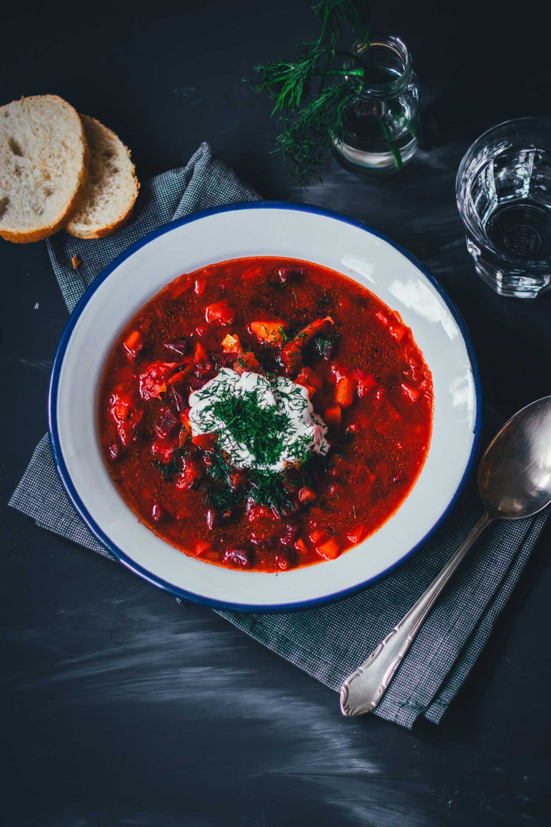Topshot von einem Teller Borschtsch (Borscht), serviert mit Saure Sahne, Dill und Brot | moeyskitchen.com