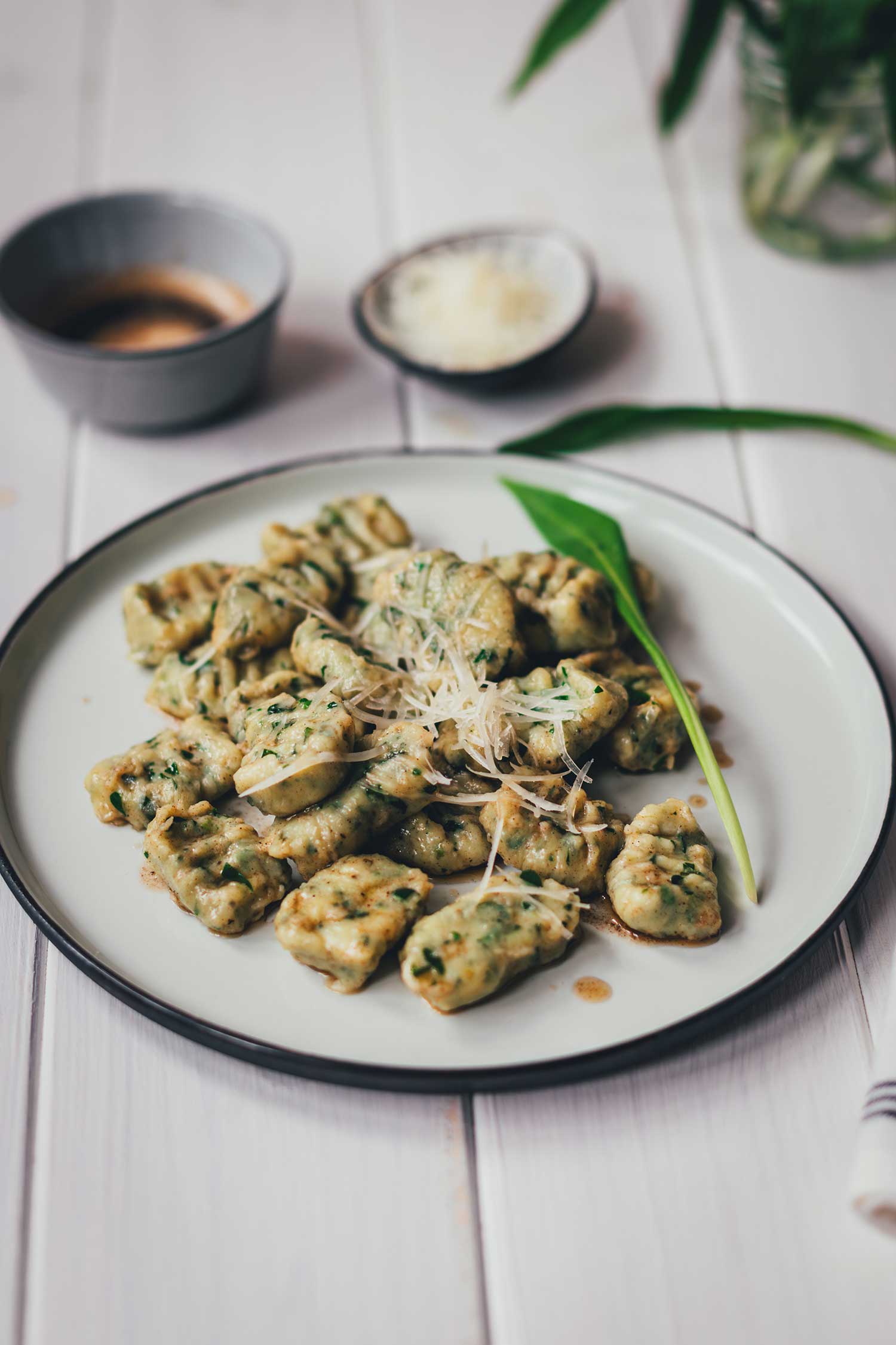 Nahaufnahme von einem Teller mit Bärlauch-Ricotta-Gnocchi, serviert mit brauner Butter und geriebenem Käse