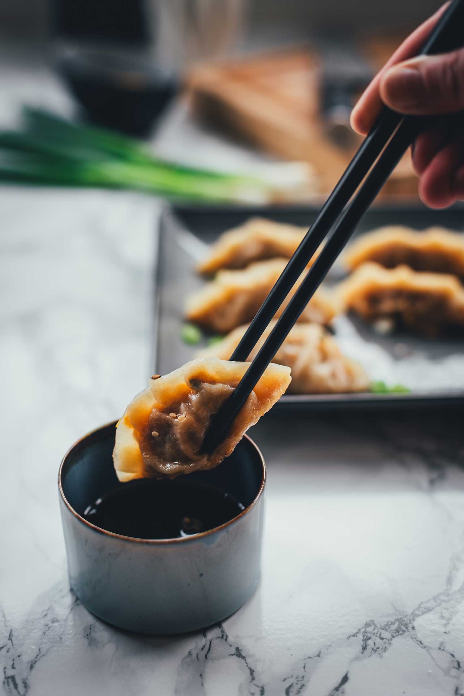 Japanische Gyoza mit Stäbchen in Sojasauce dippen