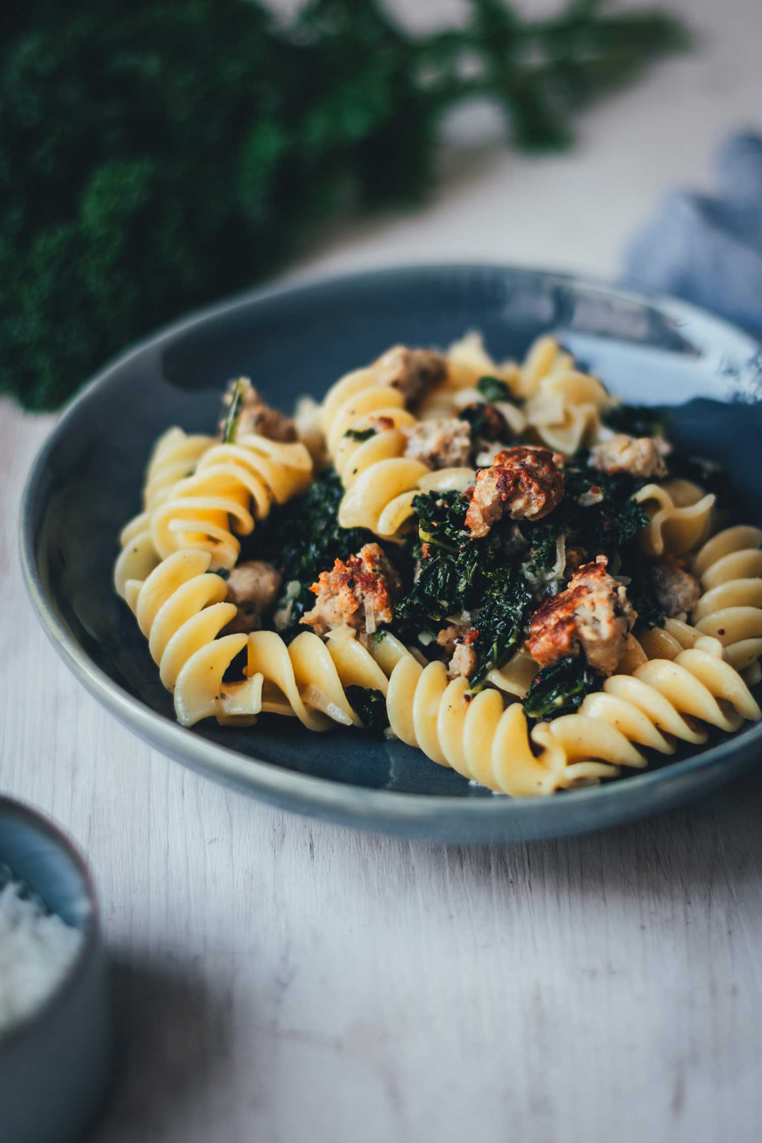 Nahaufnahme eines tiefen Tellers mit Pasta mit Grünkohl und Bratwurstbrät