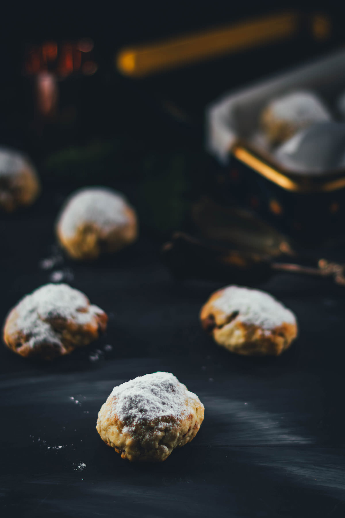 Nougat-Stollenkonfekt mit Puderzucker auf dunklem Untergrund, weiches Weihnachtsgebäck in kleinen ovalen Stücken.