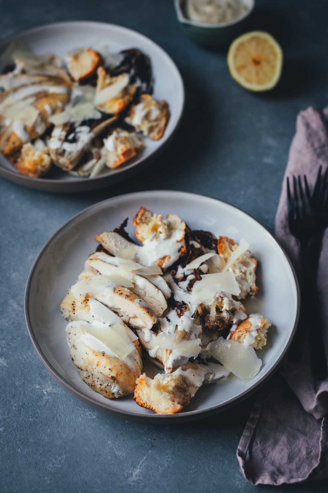 Servierfertiger Radicchio Caesar Chicken Salad auf einem Teller mit Parmesanspänen und Dressing.