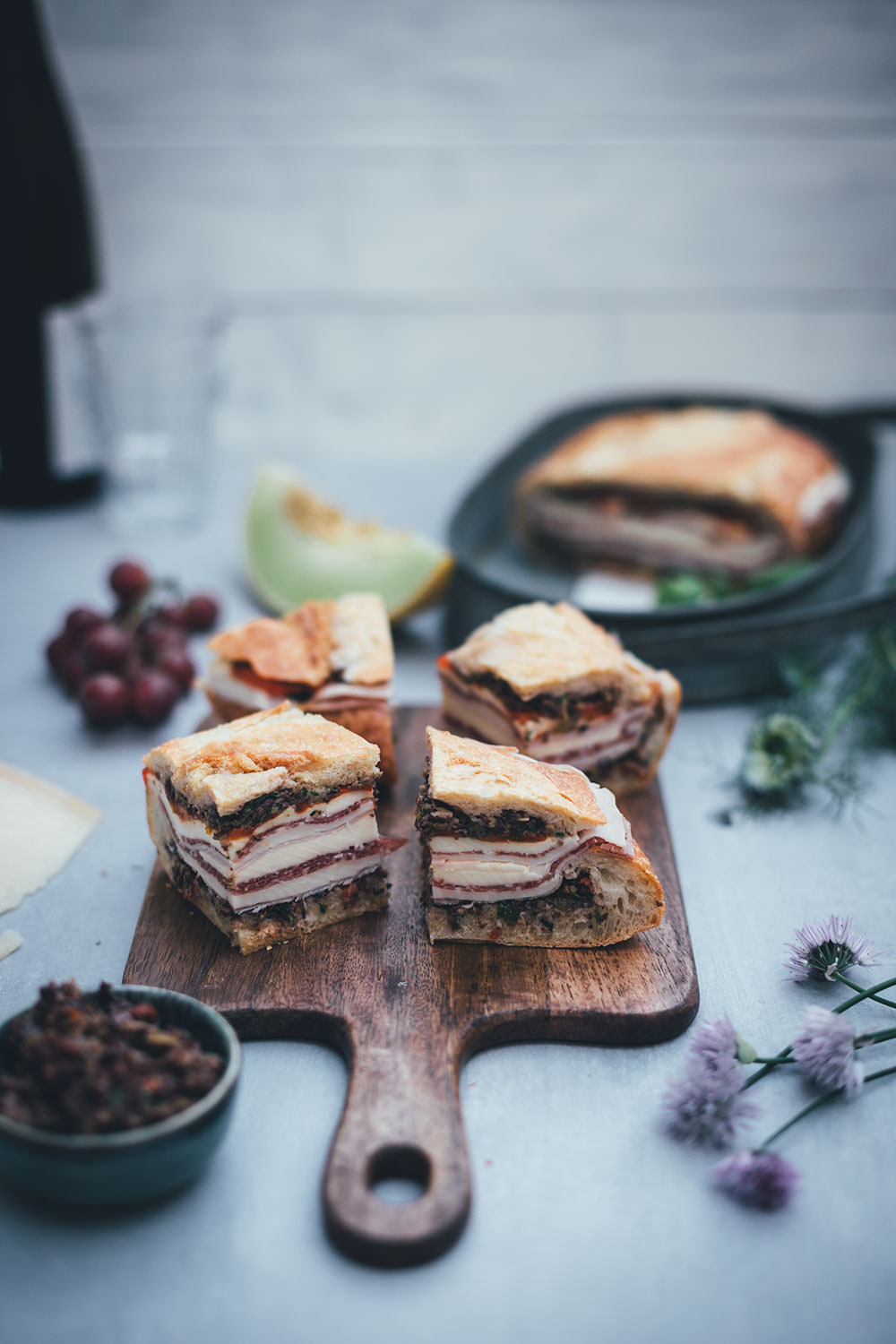 Rezept für italienisches Sandwich "Muffuletta Style" zum Picknick wie in Italien | gepresstes Weißbrot mit einer Füllung aus Oliven-Tapenade, Prosciutto Cotto, Salame Milanese, Provolone, Mozzarella und gegrillter Paprika | moeyskitchen.com #sandwich #panini #picknick #italienisch #muffuletta #brot #worlpicknickday #belegtesbrot #schnittchen #rezepte #foodblogger