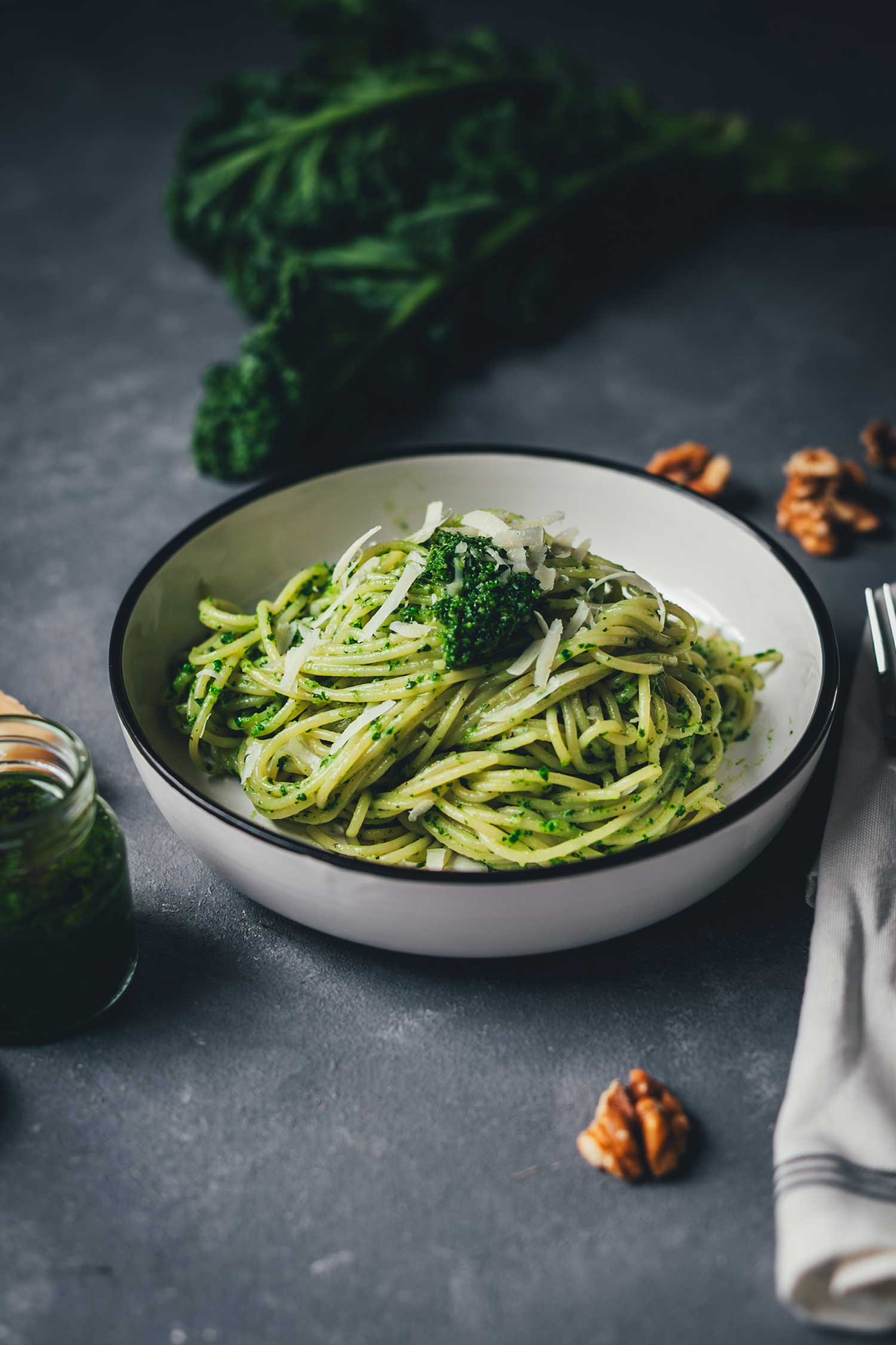 Pasta mit Grünkohl-Pesto und Parmesan auf grauem Untergrund