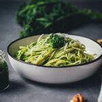 Grünkohl-Pesto mit Pasta, Walnüssen und Parmesan in einer Schale serviert