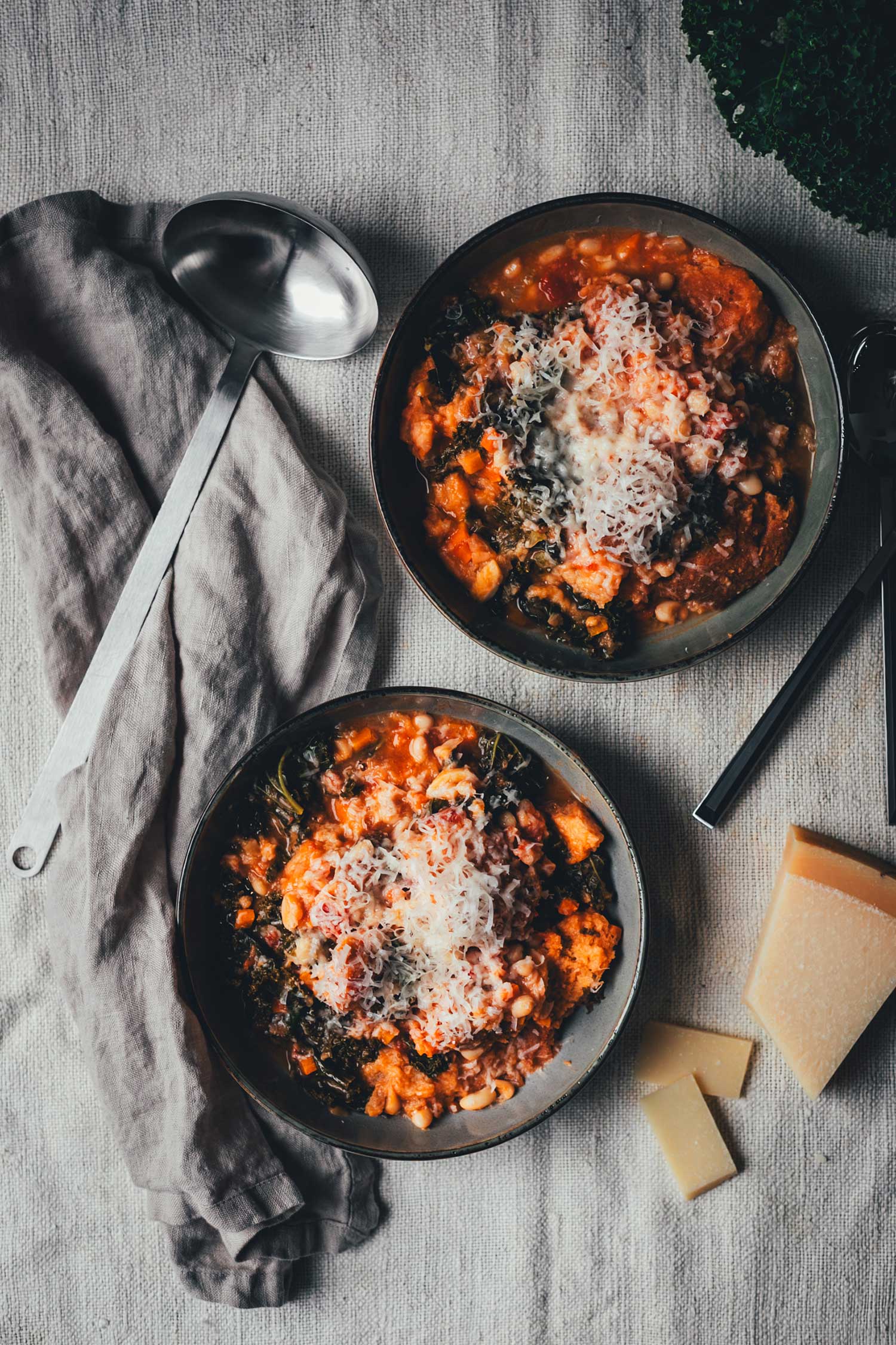 Topshot von zwei Tellern mit Ribollita, dem dicken toskanischen Eintopf mit Grünkohl, Bohnen und Brot. Getoppt mit geriebenem Parmesan | moeyskitchen.com