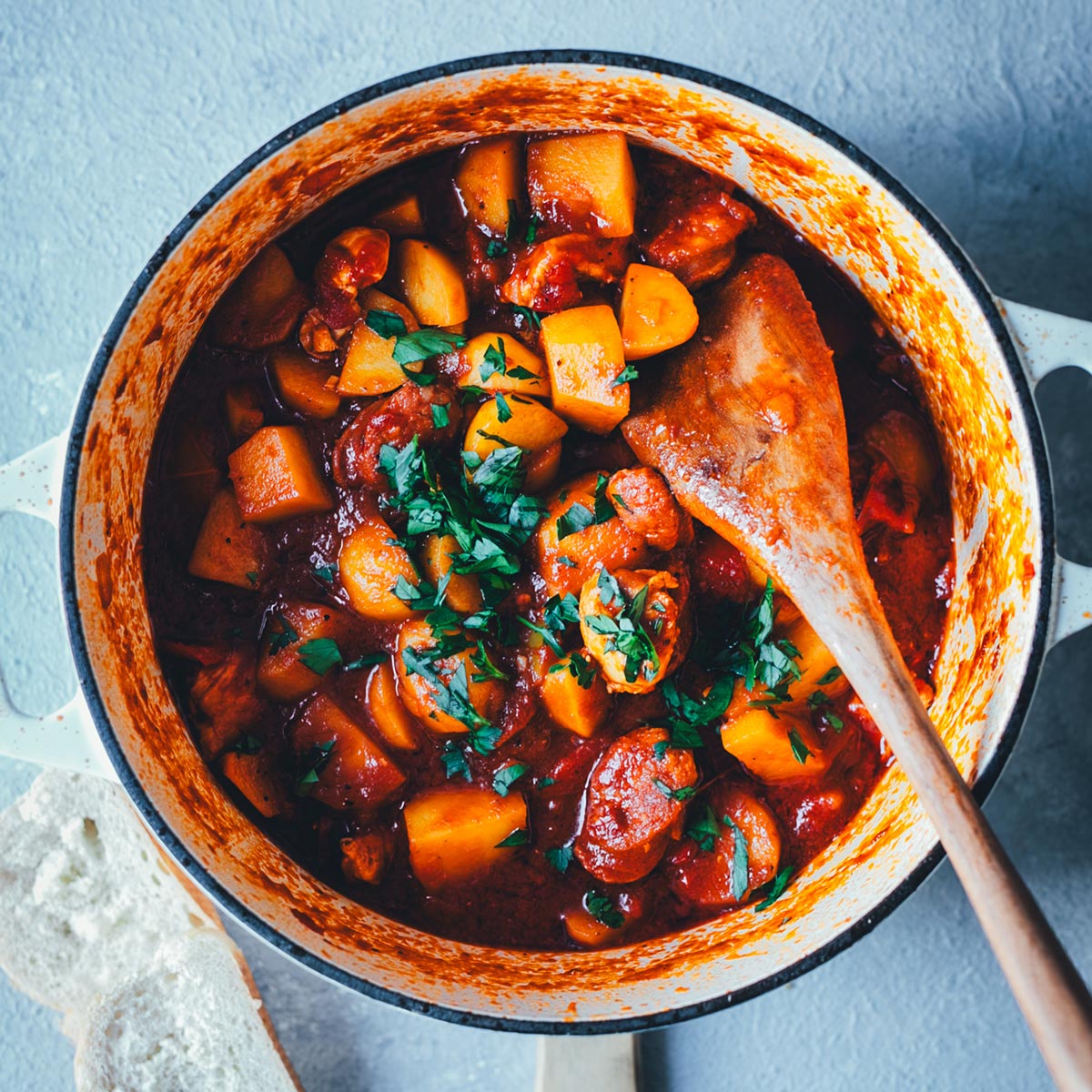 Topshot in einen großen, gusseisernen Topf, der gefüllt mit einem leckeren spanischen Kartoffel-Paprika-Eintopf ist. | moeyskitchen.com