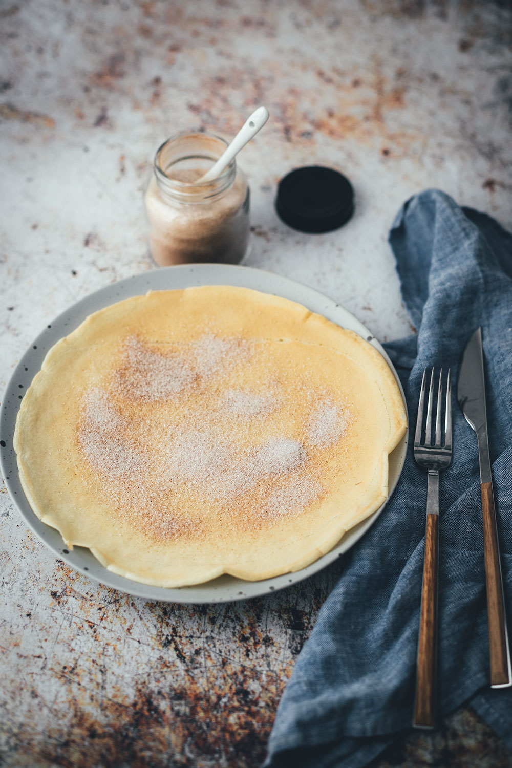 Ein einzelner Pfannkuchen auf einem Teller, mit Zucker und Zimt bestreut und schräg von oben fotografiert | moeyskitchen.com