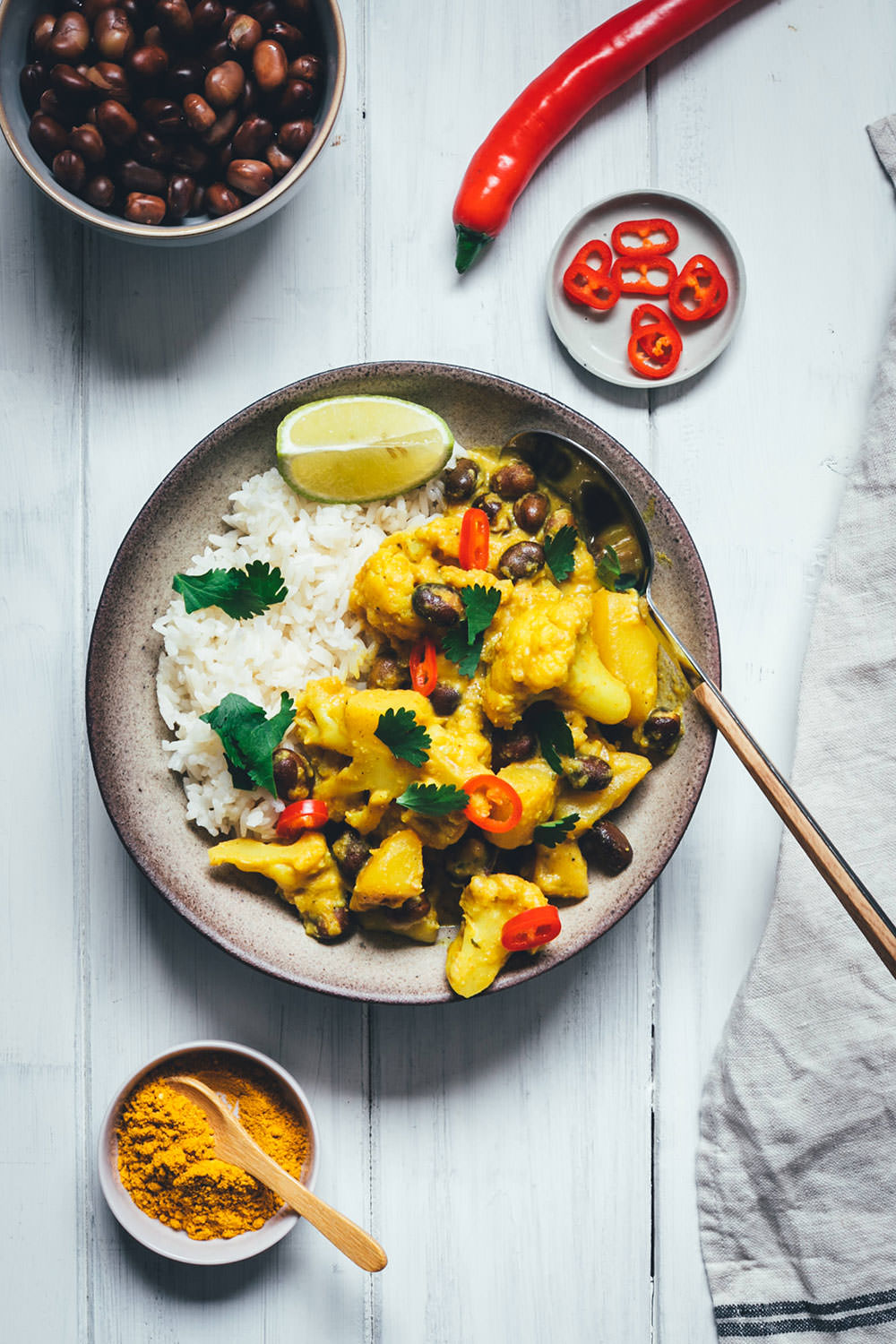 Rezept für ein würziges Blumenkohl-Kartoffel-Curry mit Ackerbohnen. Heimischer Gemüseeintopf, der an indisches Aloo Gobi bzw. Aloo Gobhi erinnert. Ackerbohnen als regionale Körnerleguminosen sind eine tolle Proteinquelle und außerdem ballaststoffreich. Und eine tolle heimische Alternative zu Kichererbsen und anderen Hülsenfrüchten. Perfekt für vegetarische und gesunde Gerichte. Madras Curry, Ingwer und Knoblauch sorgen für Würze, Chili außerdem für etwas Schärfe. Hier gibt es das einfache und unkomplizierte Rezept zum Nachkochen! | moeyskitchen.com