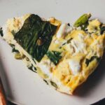 Nahaufnahme von einem Stück frisch gebackener Bärlauch-Frittata auf einem Teller mit Gabel