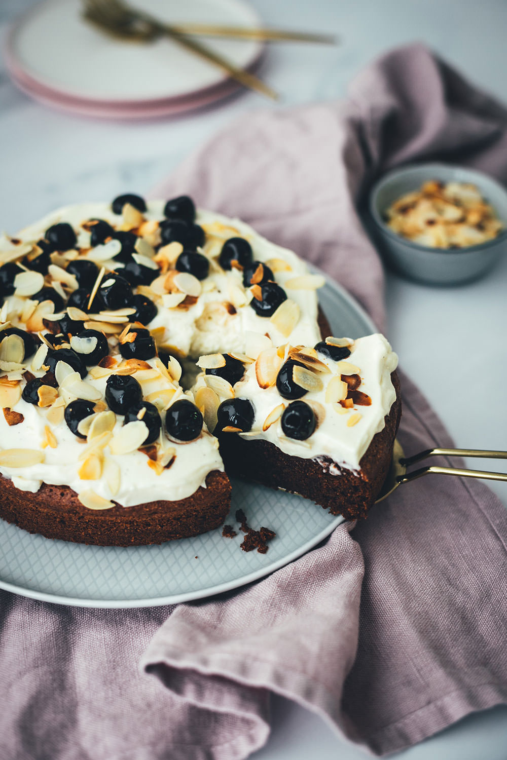 Der italienische Kuchenklassiker in neuem Gewand: Torta Caprese ist ein super saftiger Schokoladenkuchen, der ganz ohne Mehl auskommt. Stattdessen kommen hier zerkleinerte, geröstete Mandeln in den Teig. Und statt die Torta Caprese wie im Original nur mit Puderzucker zu bestreuen, serviere ich sie hier mit einer wunderbaren Mascarpone-Creme, leckeren Amarenakirschen und zusätzlich mit gerösteten Mandelblättchen. Der saftigste Schokokuchen überhaupt! | moeyskitchen.com