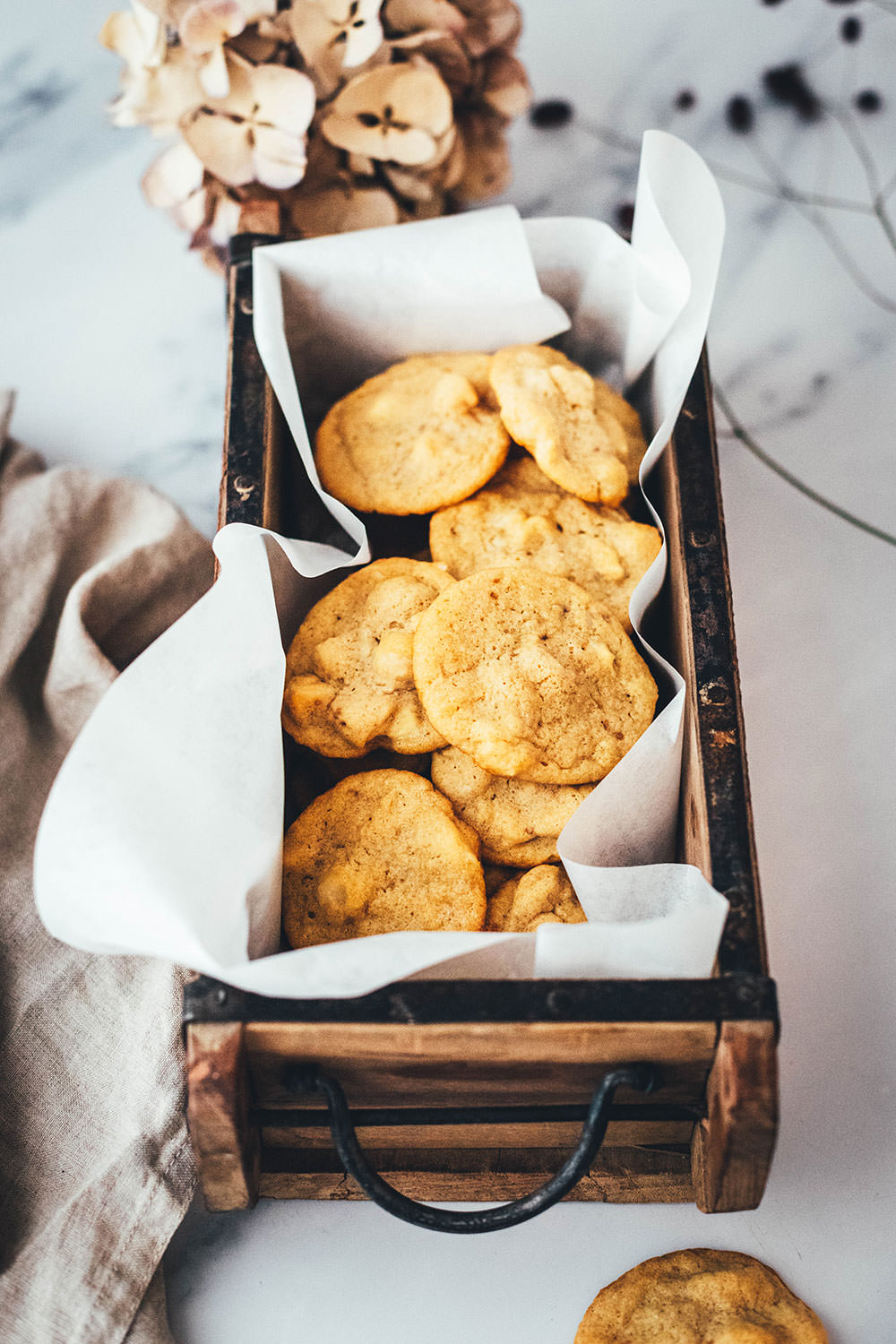 Helle, softe Macadamia-Cookies in einer Holzschachtel mit Backpapier
