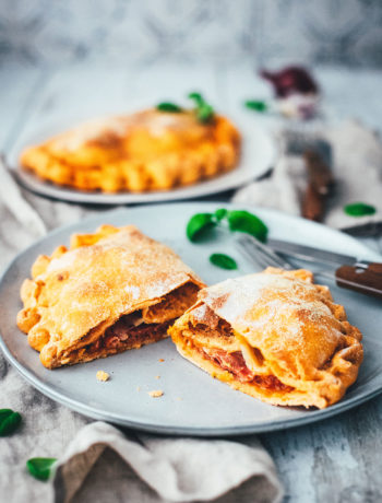 Rezept für knusprige Calzone – italienische Pizza, die als Pizzatasche gebacken wird. Mit leckerer Füllung aus Tomatensauce, Mozzarella, Schinken und Salami. Lässt sich super vorbereiten, einfrieren und frisch genießen. Ganz easy zu Hause selber machen und im normalen Ofen backen! | moeyskitchen.com