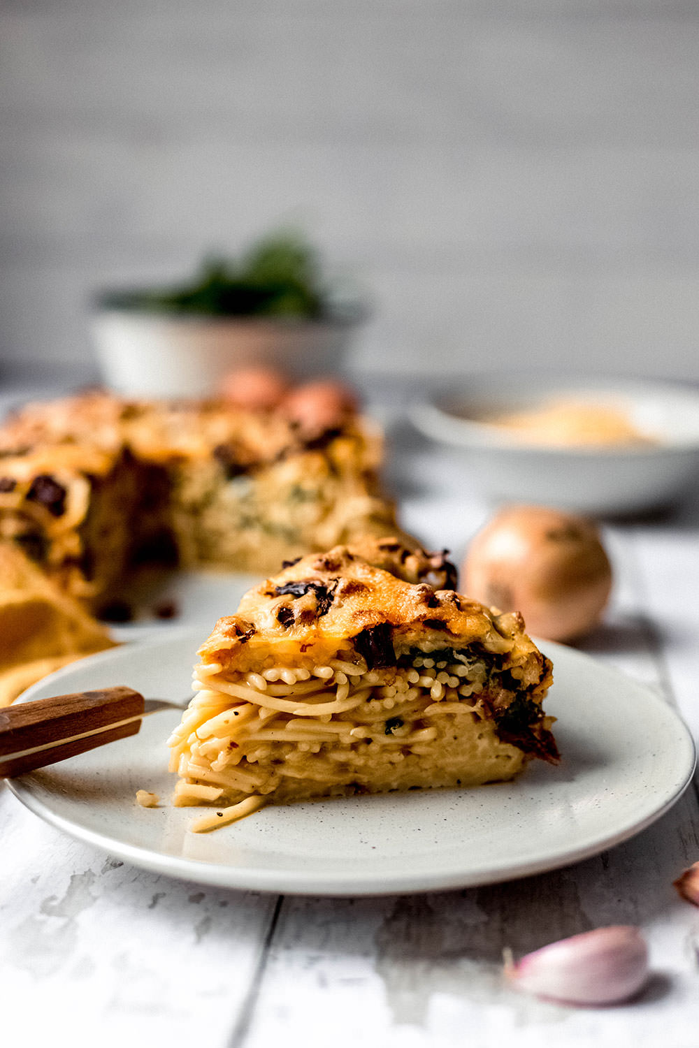 Seitliche Nahaufnahme von einem frisch angeschnittenen Stück vom Spaghetti-Kuchen. Das ist ein in einer Springform gebackener Nudelauflauf.