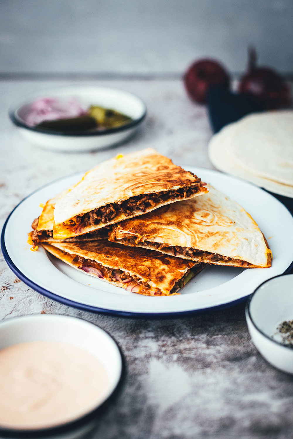 Rezept für saftige Cheeseburger Quesadillas! Das sind leckere Quesadillas mit einer Füllung aus Hackfleisch oder einer vegetarischen Hackfleisch-Alternative, reichlich Cheddar, roten Zwiebeln und Gewürzgurken. Blitzschnell zubereitet aus einfachen und ehrlichen Zutaten und so lecker! Als Vorspeise oder Hauptgericht und mit Dip serviert | moeyskitchen.com