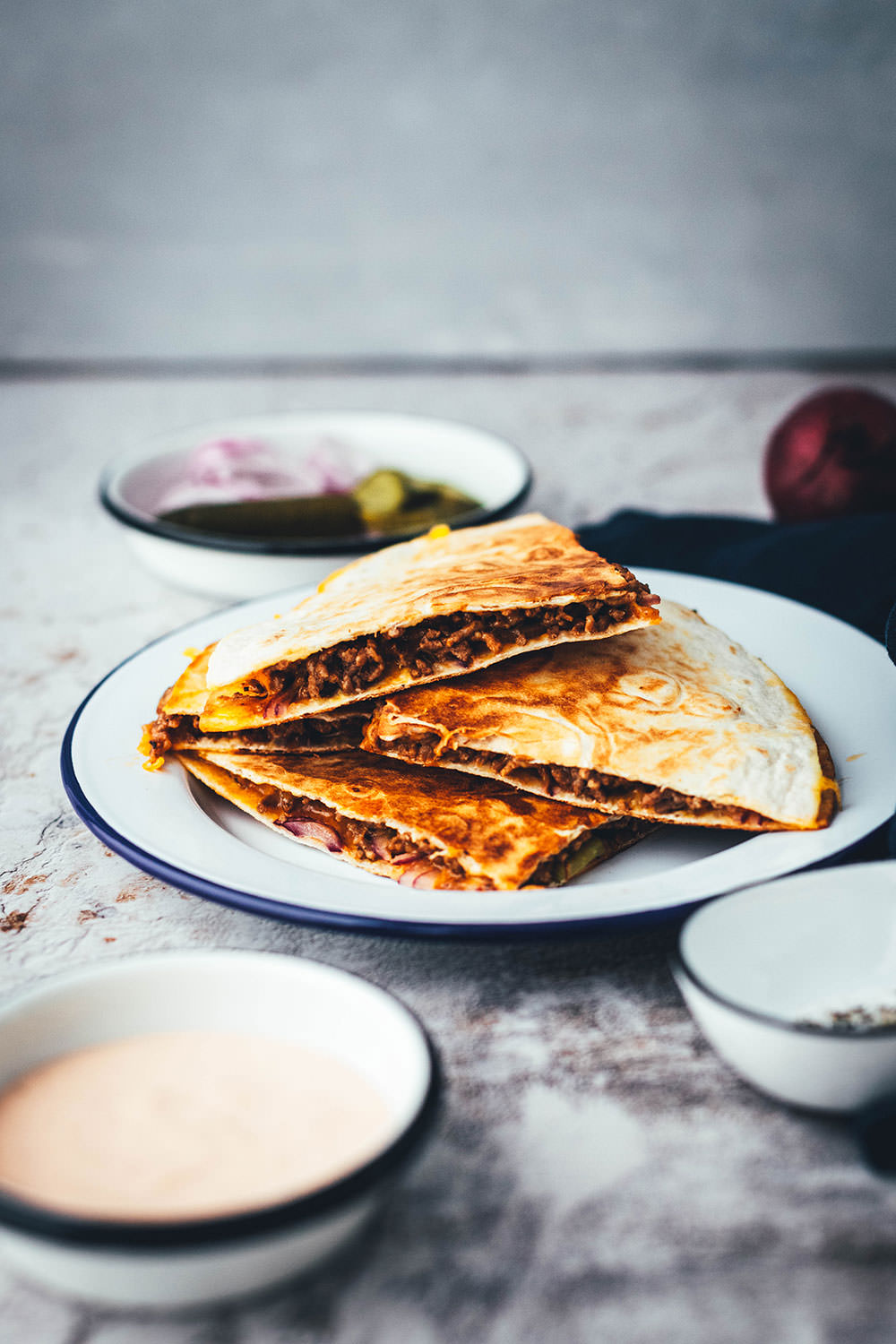 Rezept für saftige Cheeseburger Quesadillas! Das sind leckere Quesadillas mit einer Füllung aus Hackfleisch oder einer vegetarischen Hackfleisch-Alternative, reichlich Cheddar, roten Zwiebeln und Gewürzgurken. Blitzschnell zubereitet aus einfachen und ehrlichen Zutaten und so lecker! Als Vorspeise oder Hauptgericht und mit Dip serviert | moeyskitchen.com