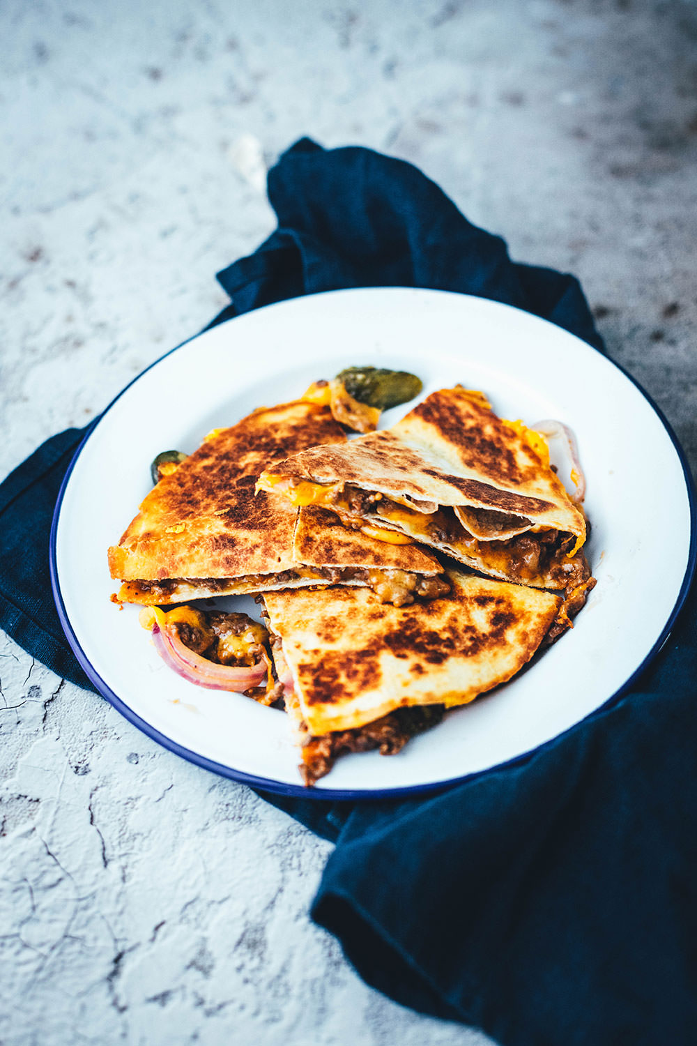Rezept für saftige Cheeseburger Quesadillas! Das sind leckere Quesadillas mit einer Füllung aus Hackfleisch oder einer vegetarischen Hackfleisch-Alternative, reichlich Cheddar, roten Zwiebeln und Gewürzgurken. Blitzschnell zubereitet aus einfachen und ehrlichen Zutaten und so lecker! Als Vorspeise oder Hauptgericht und mit Dip serviert | moeyskitchen.com