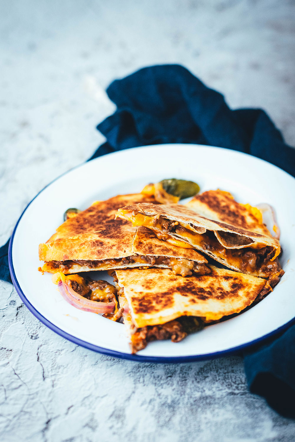 Rezept für saftige Cheeseburger Quesadillas! Das sind leckere Quesadillas mit einer Füllung aus Hackfleisch oder einer vegetarischen Hackfleisch-Alternative, reichlich Cheddar, roten Zwiebeln und Gewürzgurken. Blitzschnell zubereitet aus einfachen und ehrlichen Zutaten und so lecker! Als Vorspeise oder Hauptgericht und mit Dip serviert | moeyskitchen.com