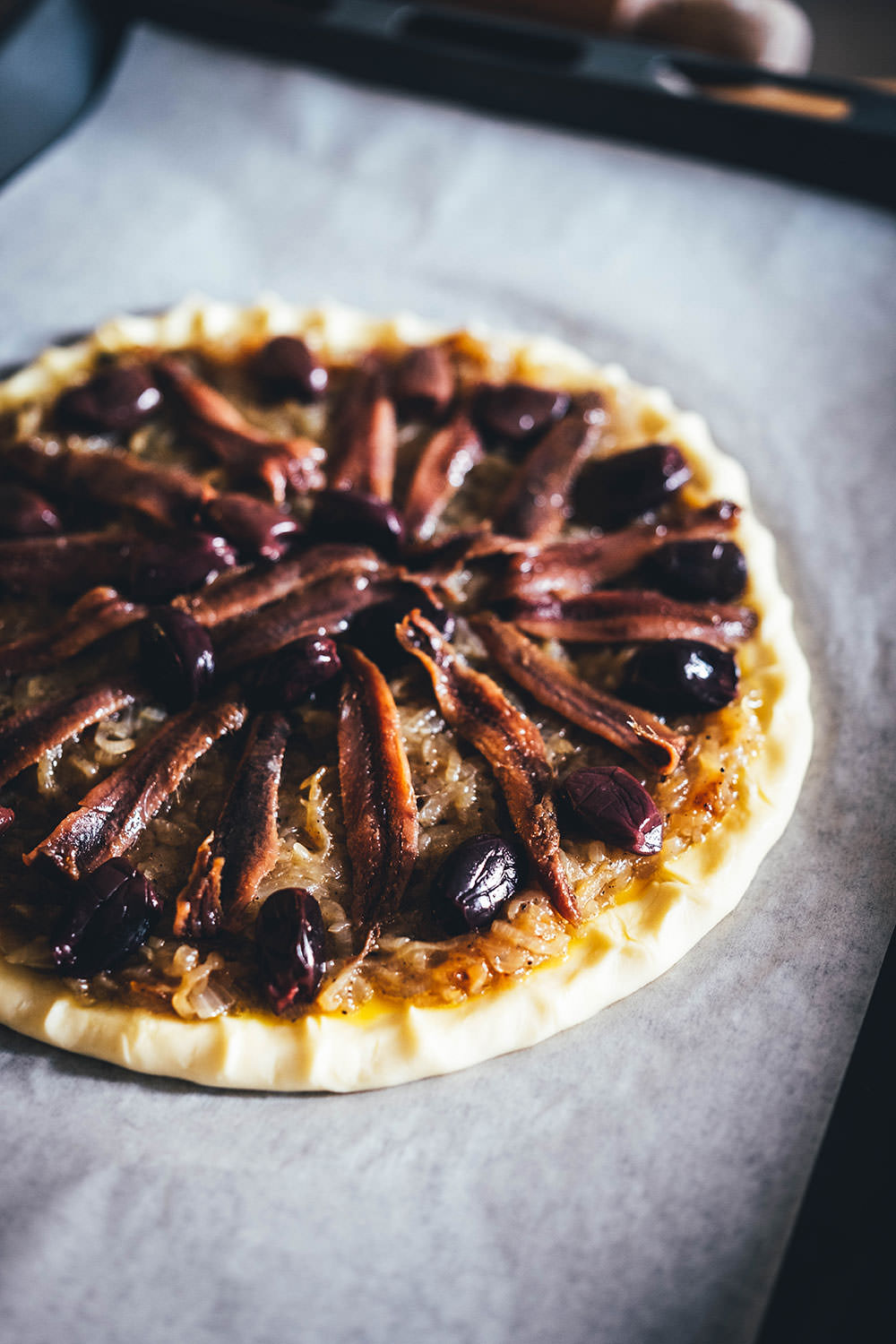 Rezept für einfache Pissaladière - herzhafter Zwiebelkuchen aus Blätterteig. Die französische Tarte wird deftig und würzig mit Sardellen (Anchovis) und schwarzen Oliven belegt. Köstlich zu einem Glas Rosé! | moeyskitchen.com