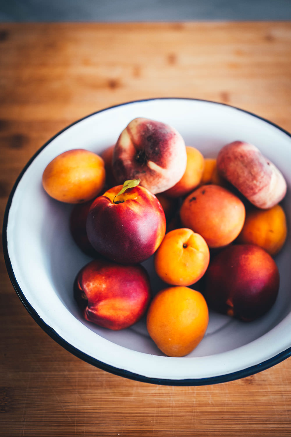Schüssel gefüllt mit spätsommerlichem Obst wie Pfirsichen, Nektarinen und Aprikosen