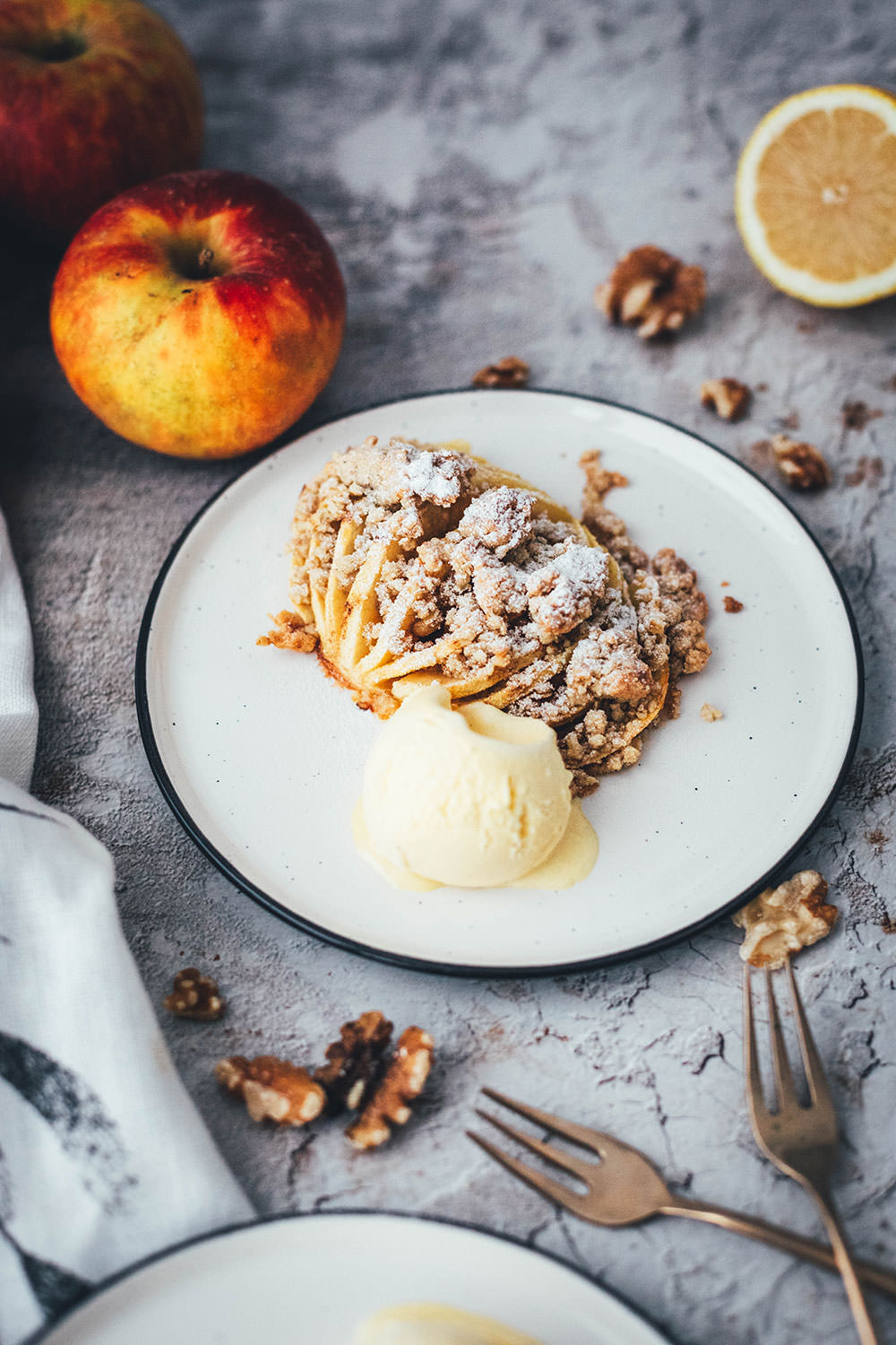 Wunderbare Rezeptidee für gebackene Äpfel mit Streuseln. Süßer Bratapfel trifft auf klassischen Apple Crumble oder Apple Crisp – heraus kommt mein Hasselback Bratapfel. Dafür werden halbierte Äpfel fächerförmig eingeschnitten, im Ofen gebacken und dann mit leckeren Streuseln bestreut. In diesen stecken gehackte Walnüsse und Haferflocken, das macht sie lecker und knusprig! | moeyskitchen.com