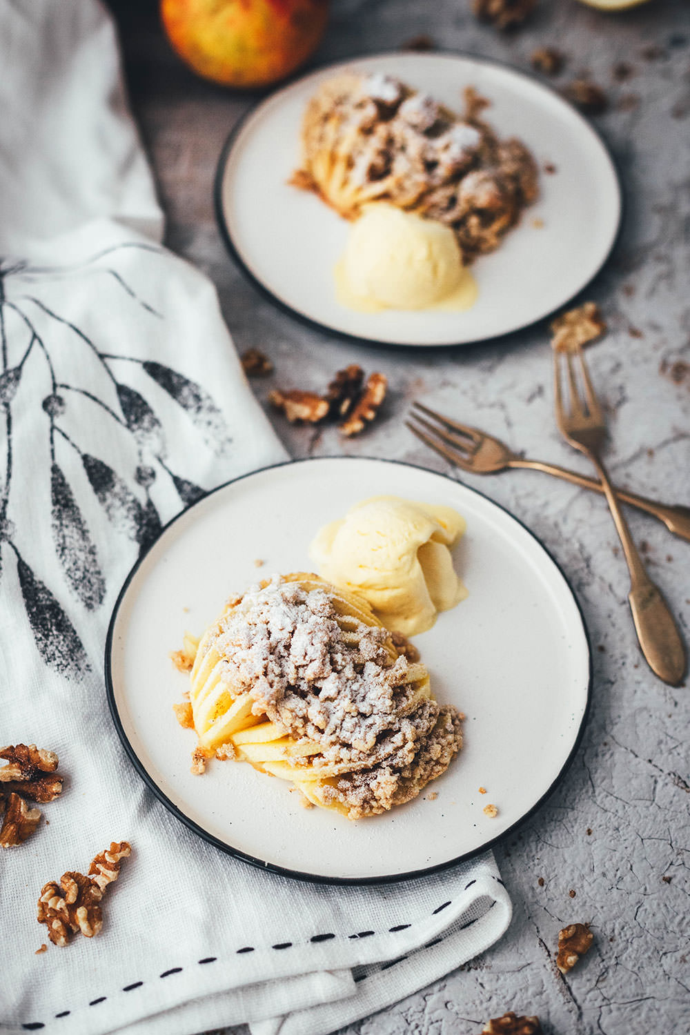 Wunderbare Rezeptidee für gebackene Äpfel mit Streuseln. Süßer Bratapfel trifft auf klassischen Apple Crumble oder Apple Crisp – heraus kommt mein Hasselback Bratapfel. Dafür werden halbierte Äpfel fächerförmig eingeschnitten, im Ofen gebacken und dann mit leckeren Streuseln bestreut. In diesen stecken gehackte Walnüsse und Haferflocken, das macht sie lecker und knusprig! | moeyskitchen.com