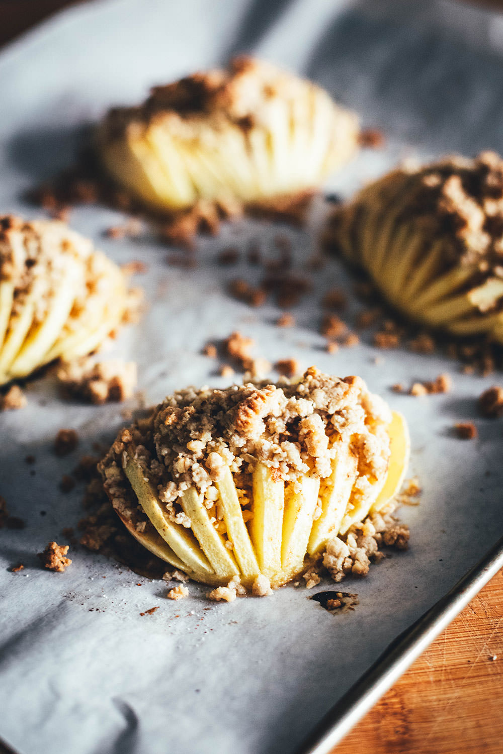 Wunderbare Rezeptidee für gebackene Äpfel mit Streuseln. Süßer Bratapfel trifft auf klassischen Apple Crumble oder Apple Crisp – heraus kommt mein Hasselback Bratapfel. Dafür werden halbierte Äpfel fächerförmig eingeschnitten, im Ofen gebacken und dann mit leckeren Streuseln bestreut. In diesen stecken gehackte Walnüsse und Haferflocken, das macht sie lecker und knusprig! | moeyskitchen.com