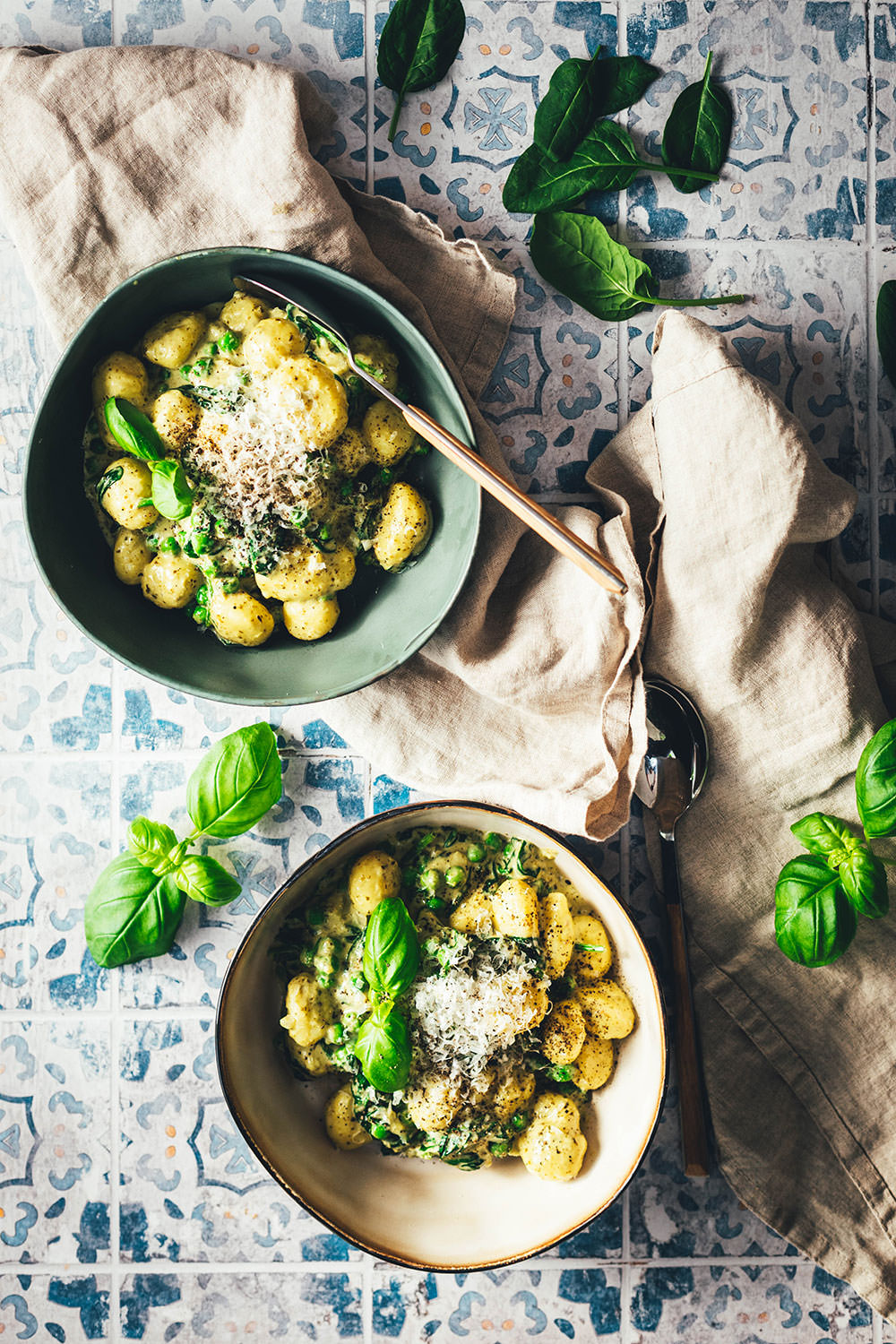 Top-Shot von zwei Schalen cremige Gnocchi mit grünem Pesto und geschmolzenem Käse – einfaches Pfannengericht für die schnelle Feierabendküche.