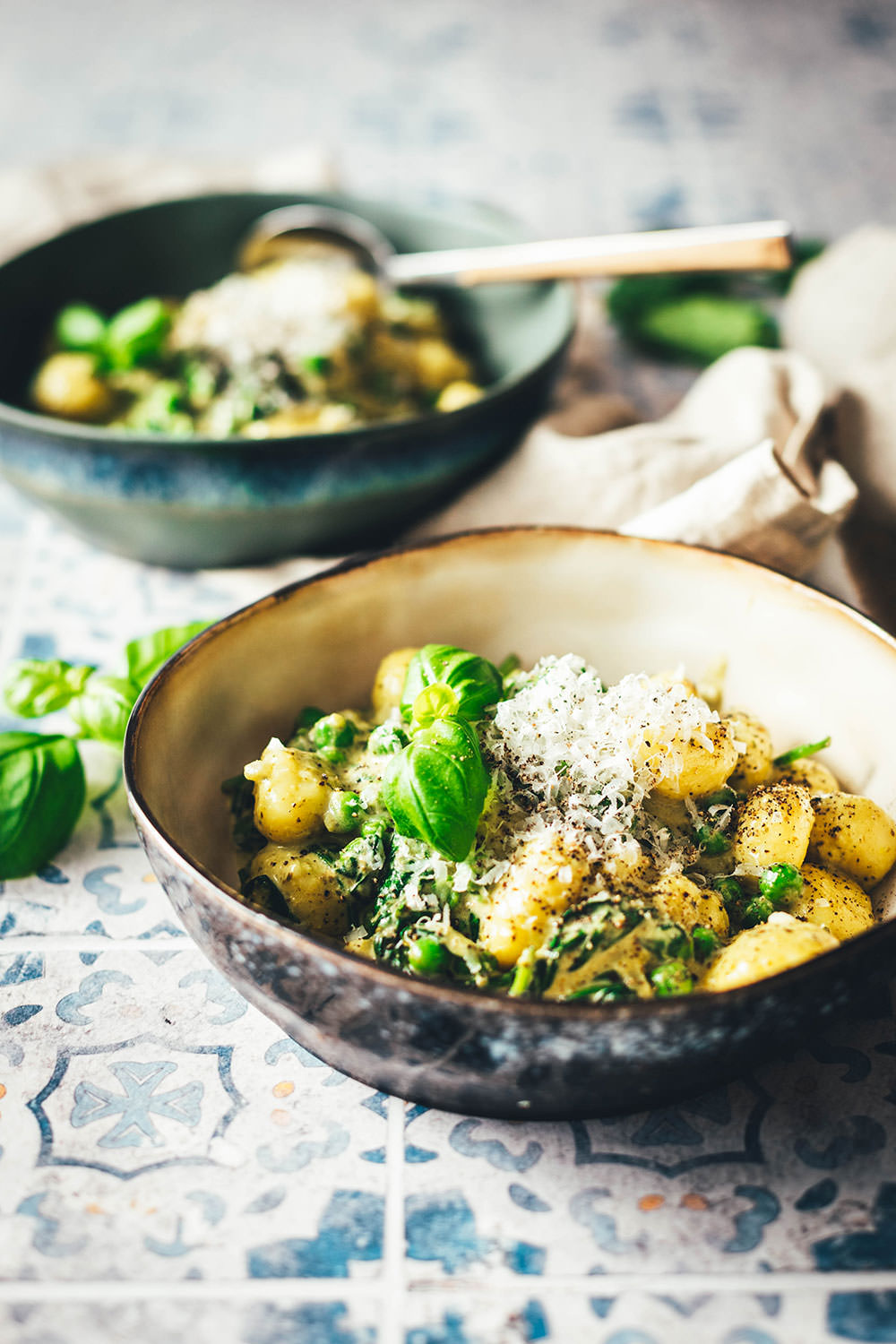 Nahaufnahme eines Tellers mit cremigen Gnocchi. Mit Spinat und Erbsen gegart, mit Pesto und reichlich Käse serviert