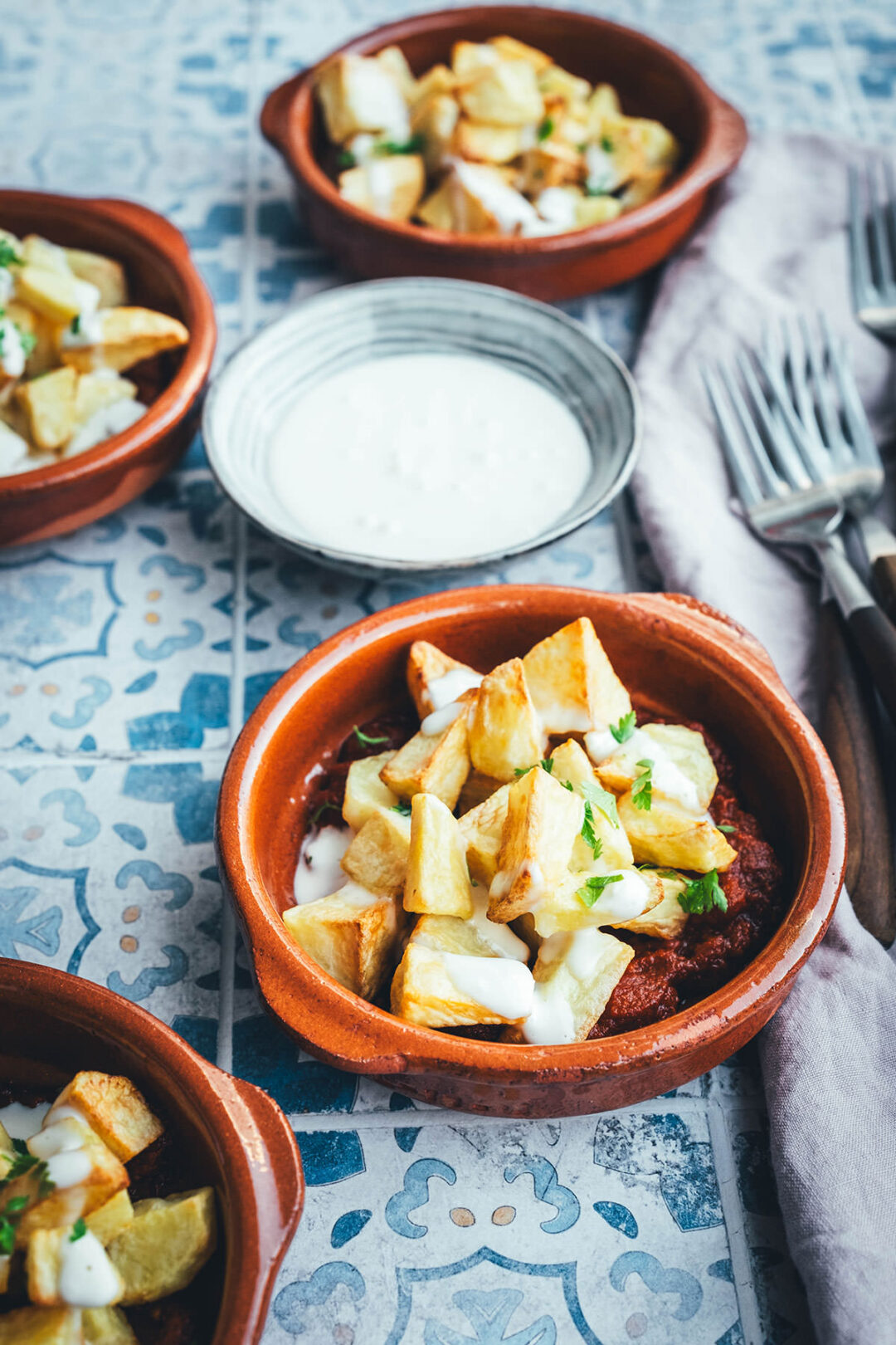 Wenn ich an spanische Tapas denke, denke ich zuerst an Patatas Bravas! Knusprig frittierte Kartoffeln mit einer scharfen roten Sauce und einer würzigen weißen Sauce. Schon als Kind habe ich sie geliebt. Jetzt habe ich mir den Spanien-Urlaub nach Hause geholt und bereite meine Patatas Bravas einfach im Air Fryer zu. Das geht super schnell und unkompliziert! So hat man in kürzester Zeit die perfekte Urlaubserinnerung auf dem Tisch stehen. Hier gibt es das köstliche Rezept für Kartoffelwürfel mit scharfer Tomatensauce (Salsa brava) und einer schnellen Knoblauchmayonnaise (Aioli)! | moeyskitchen.com