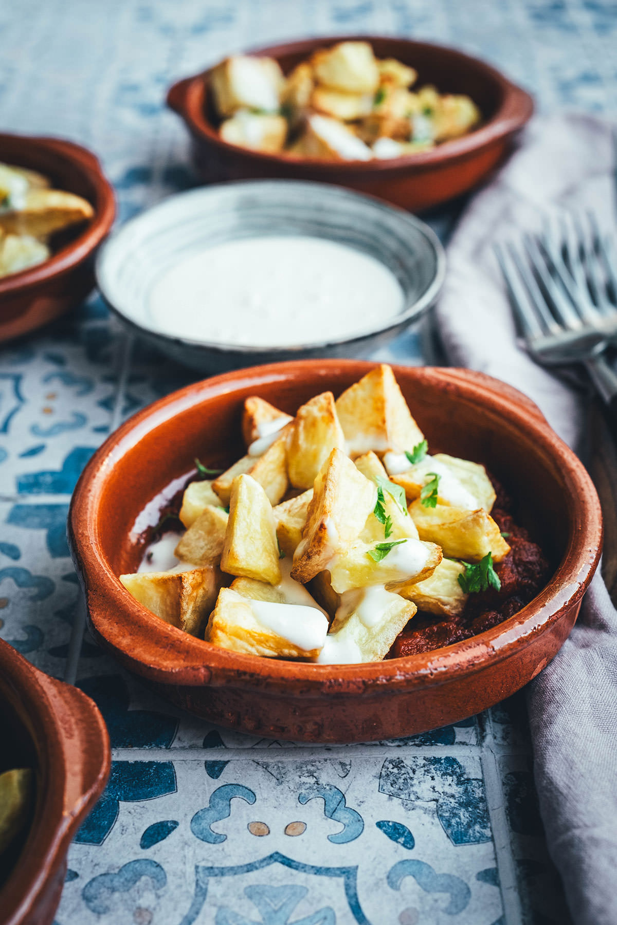 Wenn ich an spanische Tapas denke, denke ich zuerst an Patatas Bravas! Knusprig frittierte Kartoffeln mit einer scharfen roten Sauce und einer würzigen weißen Sauce. Schon als Kind habe ich sie geliebt. Jetzt habe ich mir den Spanien-Urlaub nach Hause geholt und bereite meine Patatas Bravas einfach im Air Fryer zu. Das geht super schnell und unkompliziert! So hat man in kürzester Zeit die perfekte Urlaubserinnerung auf dem Tisch stehen. Hier gibt es das köstliche Rezept für Kartoffelwürfel mit scharfer Tomatensauce (Salsa brava) und einer schnellen Knoblauchmayonnaise (Aioli)! | moeyskitchen.com