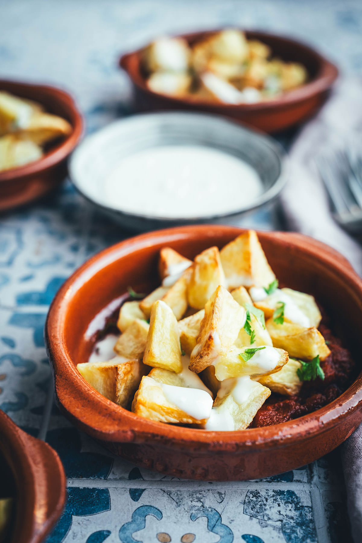 Wenn ich an spanische Tapas denke, denke ich zuerst an Patatas Bravas! Knusprig frittierte Kartoffeln mit einer scharfen roten Sauce und einer würzigen weißen Sauce. Schon als Kind habe ich sie geliebt. Jetzt habe ich mir den Spanien-Urlaub nach Hause geholt und bereite meine Patatas Bravas einfach im Air Fryer zu. Das geht super schnell und unkompliziert! So hat man in kürzester Zeit die perfekte Urlaubserinnerung auf dem Tisch stehen. Hier gibt es das köstliche Rezept für Kartoffelwürfel mit scharfer Tomatensauce (Salsa brava) und einer schnellen Knoblauchmayonnaise (Aioli)! | moeyskitchen.com