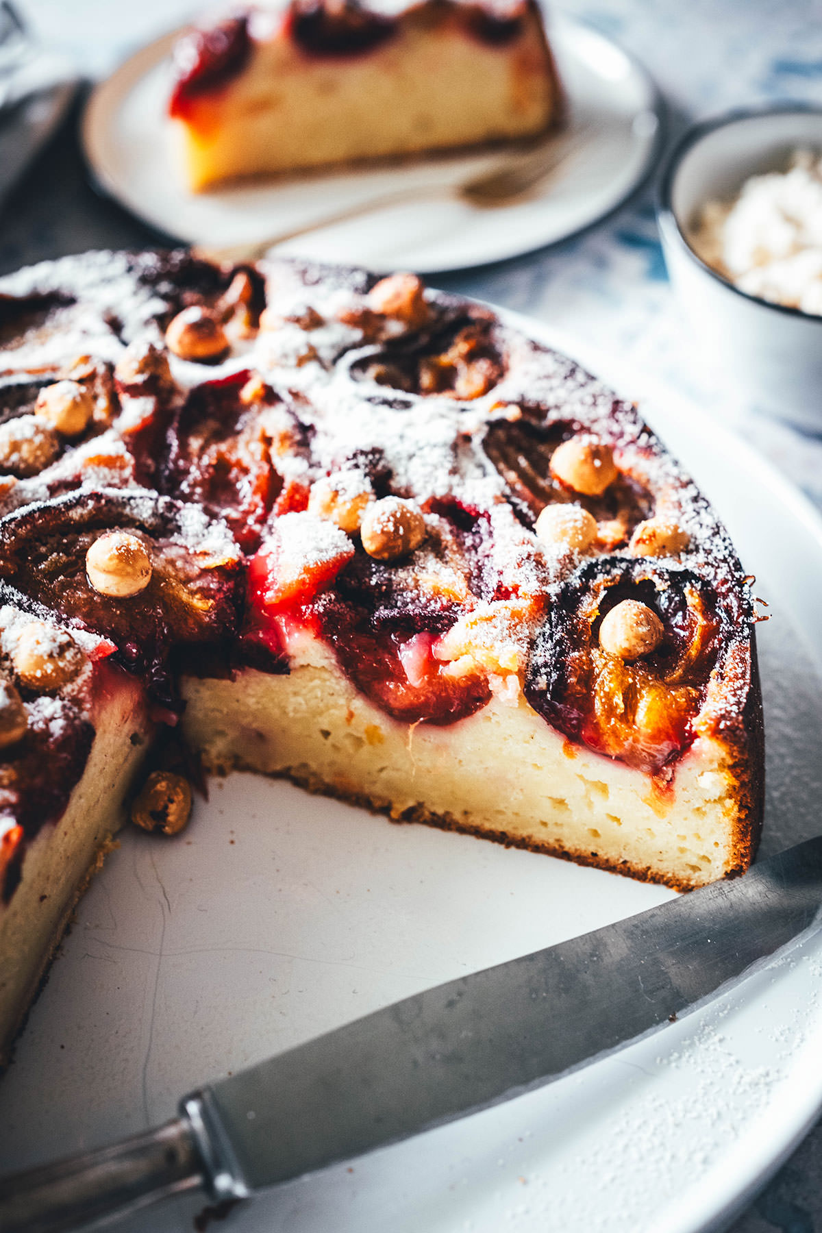 Rezept für einen wunderbaren Spätsommer-Kuchen: Mein italienischer Pflaumenkuchen ist blitzschnell zusammengerührt. Durch Ricotta und Eier wird der Kuchen extrem saftig. Geröstete Haselnusskerne sorgen für eine knackige Komponente und werden außerdem mit Puderzucker vermixt nach dem Backen über den Kuchen gestreut. Eine spannende Alternative zu klassischem Zwetschgendatschi oder Pflaumenkuchen mit Streuseln! | moeyskitchen.com