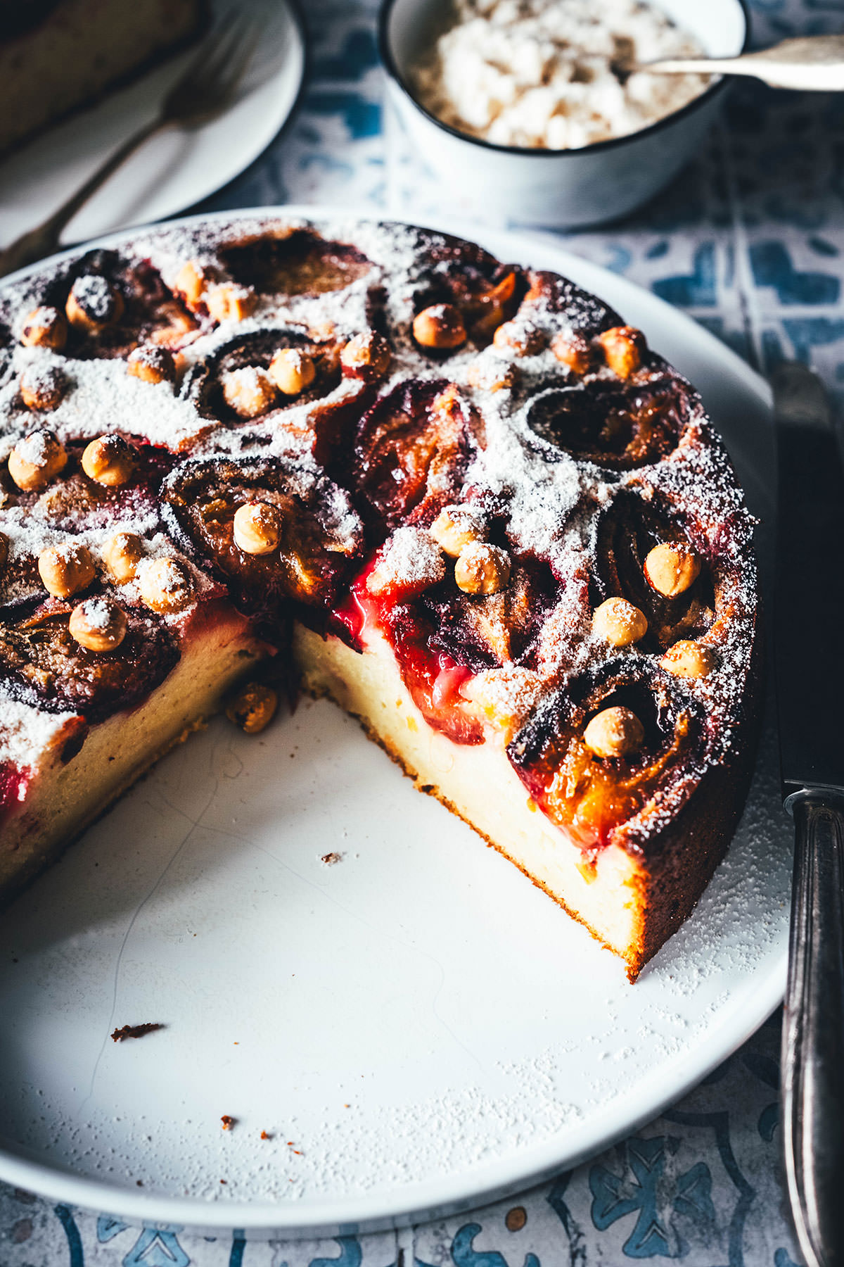 Rezept für einen wunderbaren Spätsommer-Kuchen: Mein italienischer Pflaumenkuchen ist blitzschnell zusammengerührt. Durch Ricotta und Eier wird der Kuchen extrem saftig. Geröstete Haselnusskerne sorgen für eine knackige Komponente und werden außerdem mit Puderzucker vermixt nach dem Backen über den Kuchen gestreut. Eine spannende Alternative zu klassischem Zwetschgendatschi oder Pflaumenkuchen mit Streuseln! | moeyskitchen.com