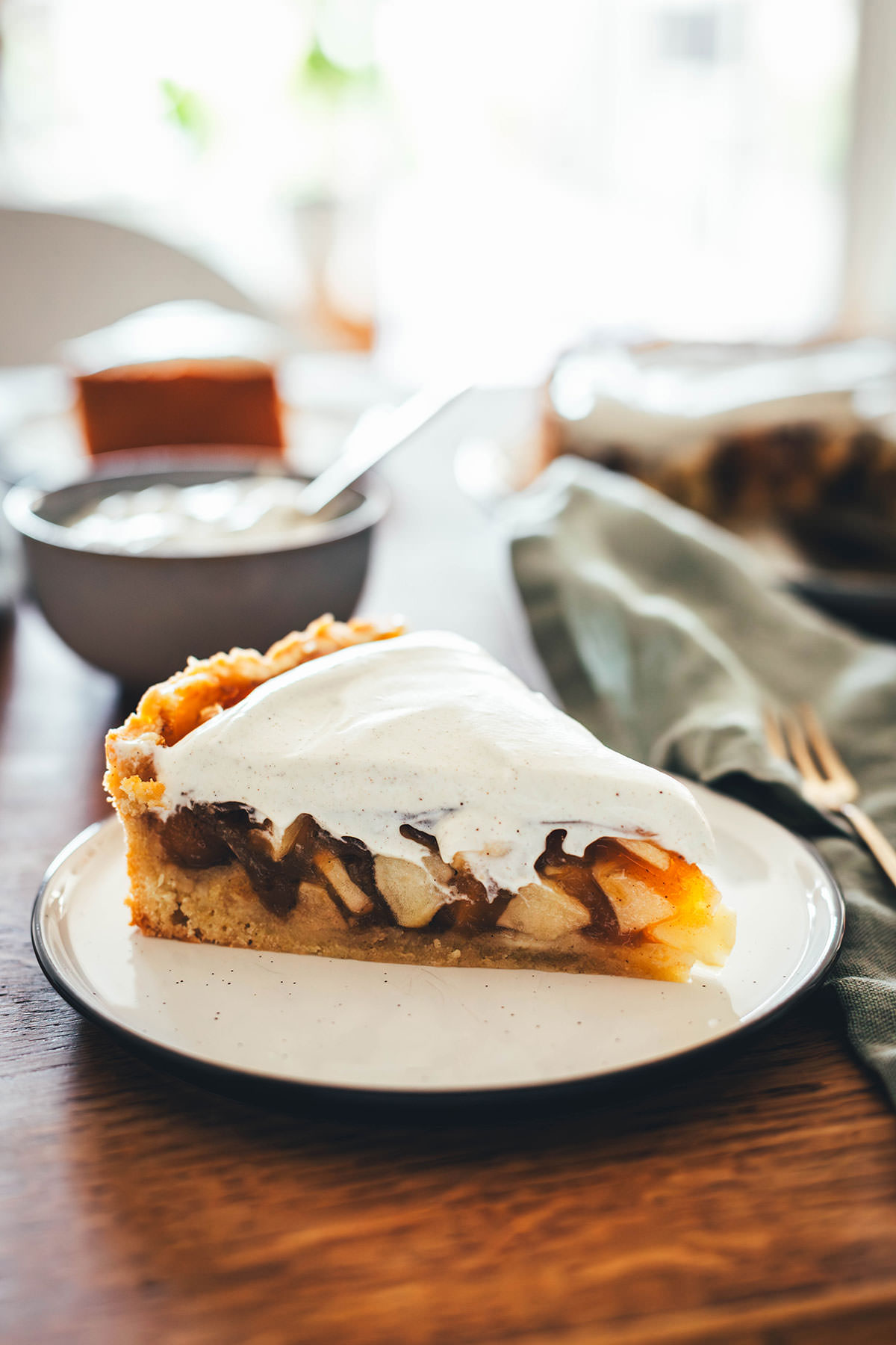 Rezept für Apfelkuchen mit knusprigem Mürbeteigboden und einer Füllung mit Äpfeln. Vanillepuddingpulver wird hier einfach mit Apfelsaft angerührt und mit Apfelstückchen gefüllt. Das ergibt die köstliche Füllung für diesen simplen Apfel-Pudding-Kuchen. Getoppt wird der Kuchen dann mit einer ganz lockeren Schmandcreme mit Vanille. | moeyskitchen.com