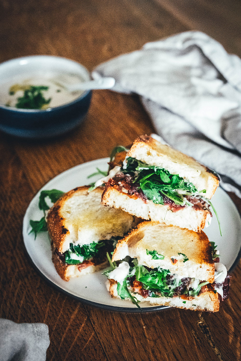 Rezept für veganes Hummus-Sandwich: knuspriges Brot mit selbst gemachtem weißen Bohnen-Hummus, karamellisierten Zwiebeln und getrockneten Tomaten. Mit Rucola und Petersilie verfeinert und zum Mittagessen oder als Stulle für unterwegs serviert. Eine vegane Alternative zum klassischen Butterbrot! | moeyskitchen.com