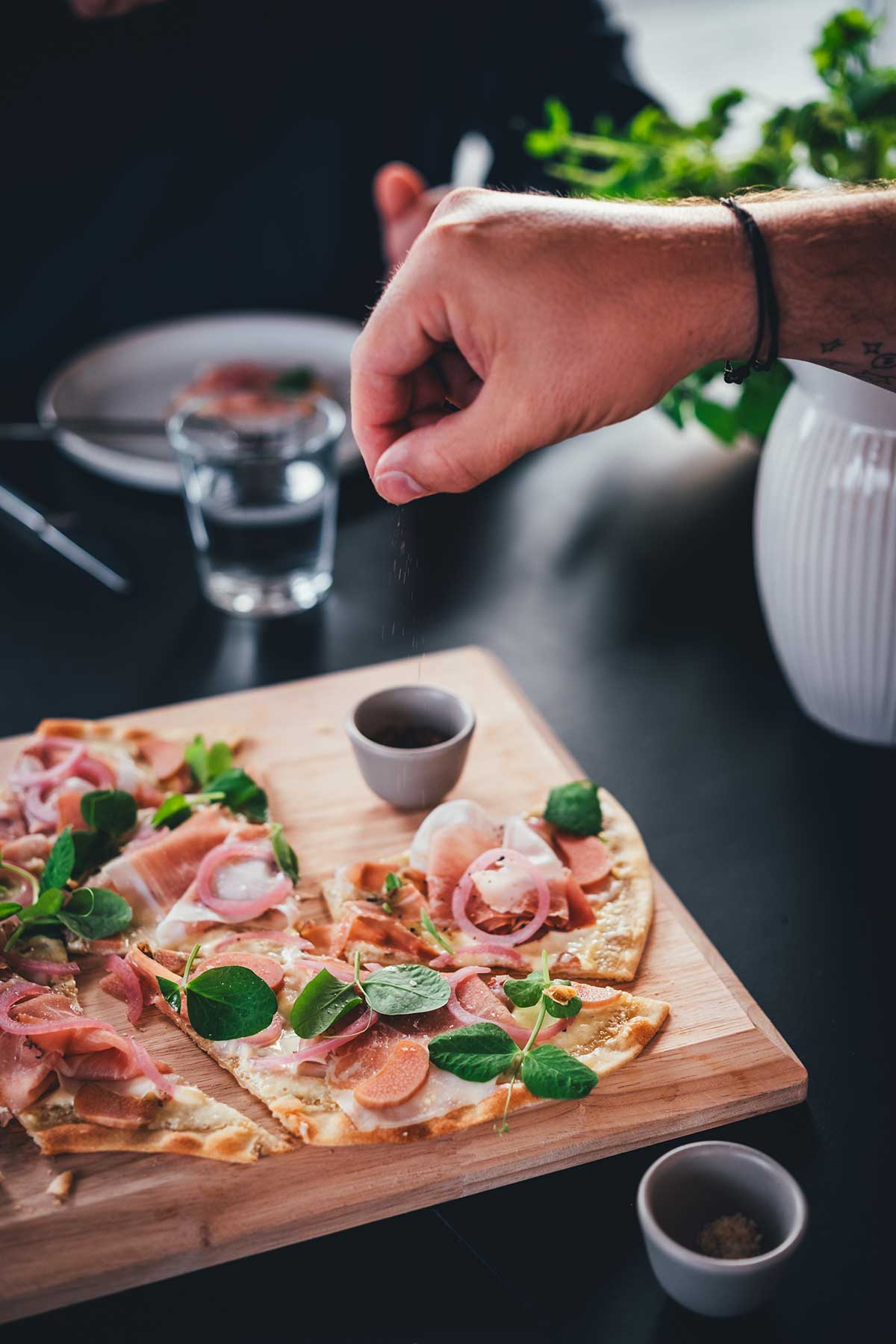 Knuspriger Flammkuchen wird mit geräuchertem Meersalz bestreut. | moeyskitchen.com