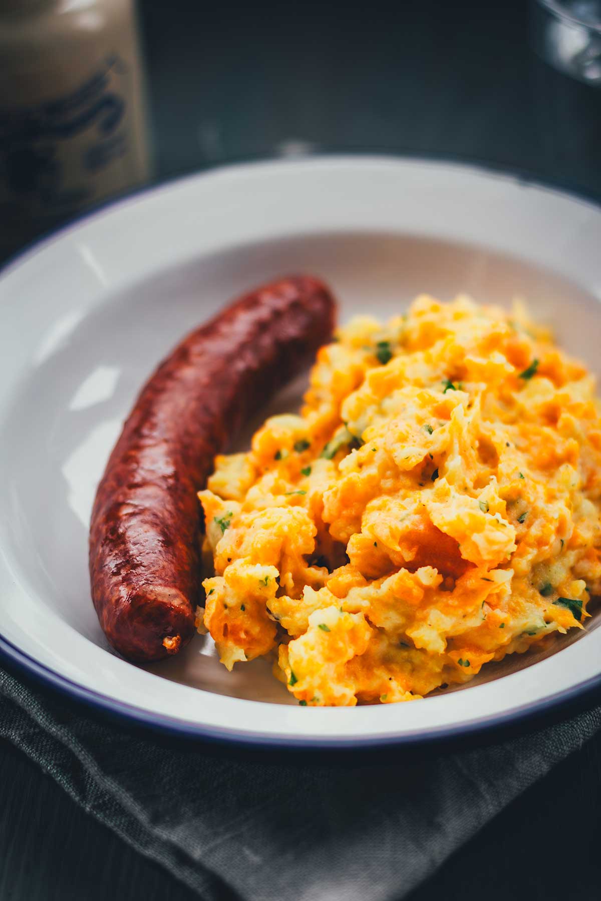 Rezept für einfache und deftige Hausmannskost: Kartoffel-Möhren-Stampf einfach selbst zubereitet. Serviert mit würziger Mettwurst ist das das perfekte Abendessen in der kalten Jahreszeit und genau das richtige für den Herbst. | moeyskitchen.com