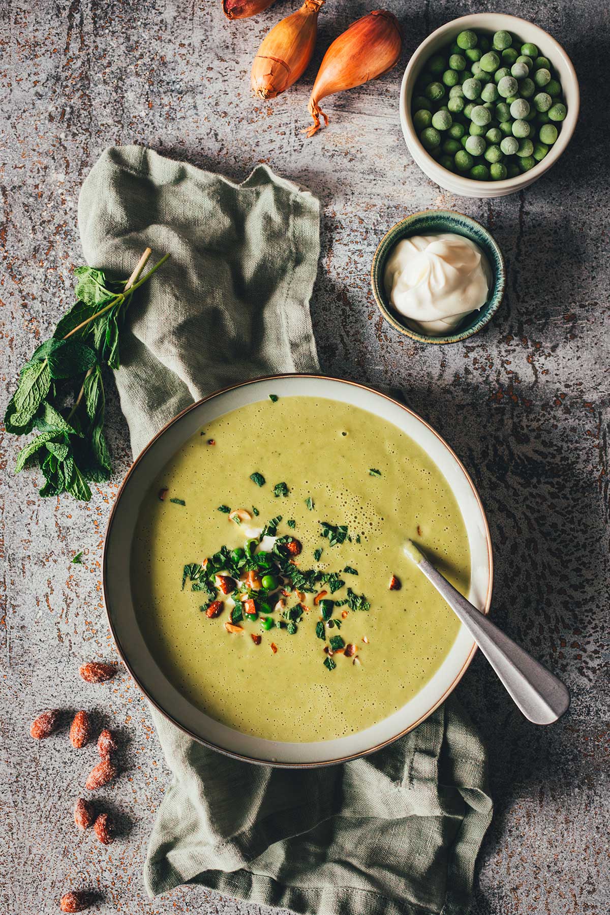 Erbsensuppe mit Minze und Crème fraîche in einer Schale, garniert mit Kräutern und Mandeln. | moeyskitchen.com