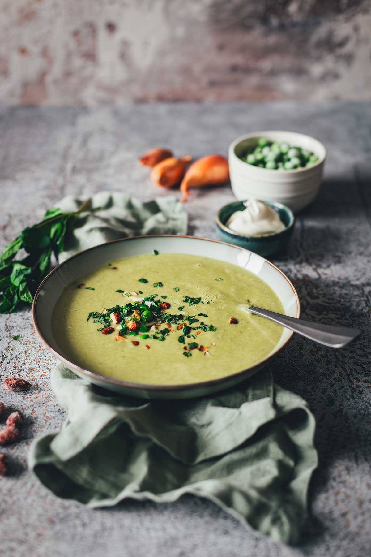 Erbsensuppe mit Minze und Crème fraîche in einer Schale, garniert mit Kräutern und Mandeln. | moeyskitchen.com